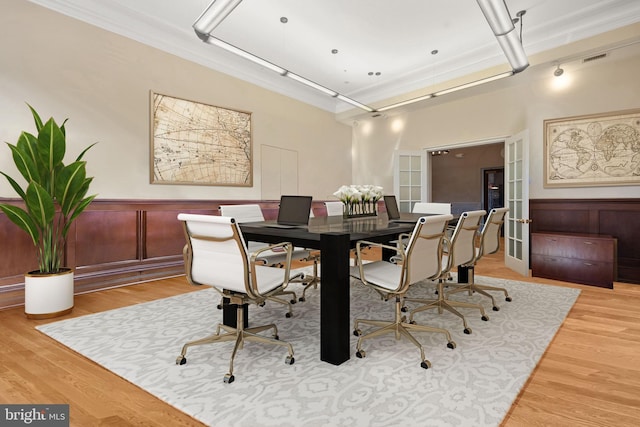 dining area with crown molding, french doors, and light wood-type flooring