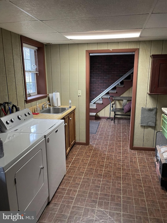 washroom with wood walls, cabinets, separate washer and dryer, and sink