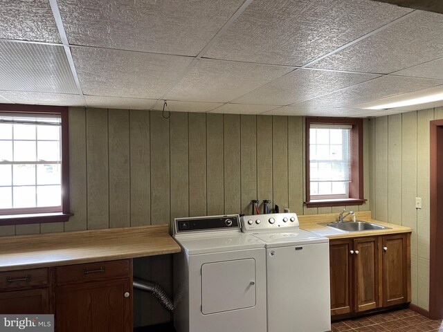 laundry room with washer and dryer, cabinets, sink, and wooden walls