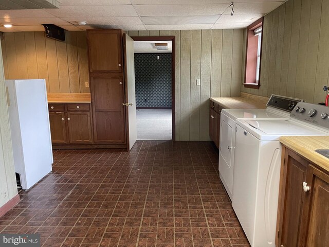 laundry room featuring wood walls, cabinets, and washing machine and clothes dryer