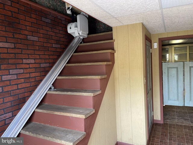 stairway featuring a drop ceiling