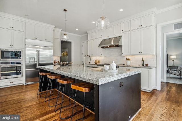 kitchen with decorative light fixtures, white cabinets, stainless steel appliances, hardwood / wood-style floors, and sink