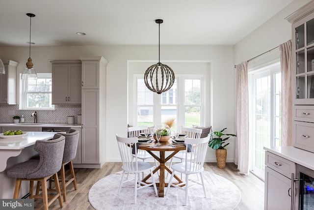 dining area featuring an inviting chandelier, light hardwood / wood-style flooring, a wealth of natural light, and sink