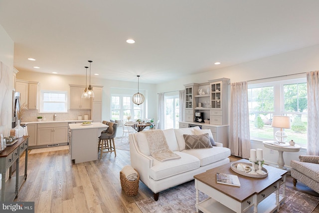 living room with sink, a healthy amount of sunlight, and light wood-type flooring