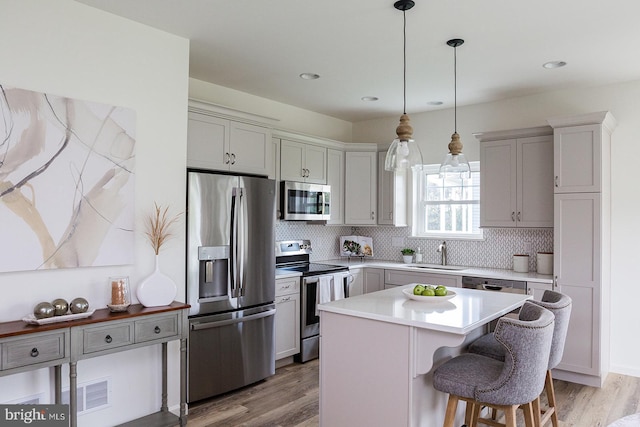 kitchen with a kitchen island, light hardwood / wood-style floors, tasteful backsplash, and appliances with stainless steel finishes