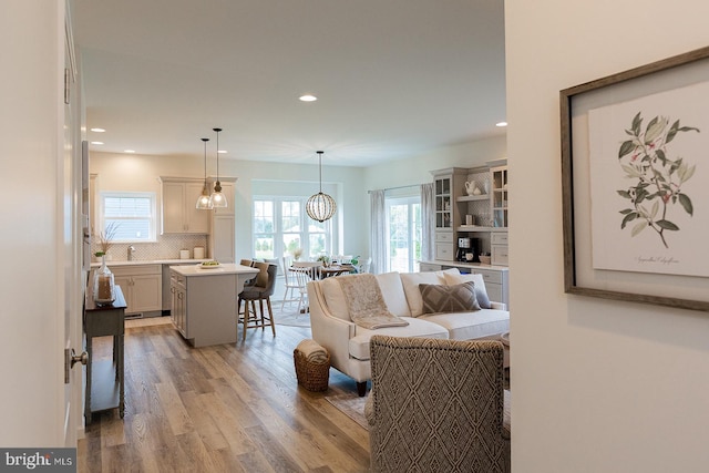 living room featuring light hardwood / wood-style flooring, sink, and a notable chandelier