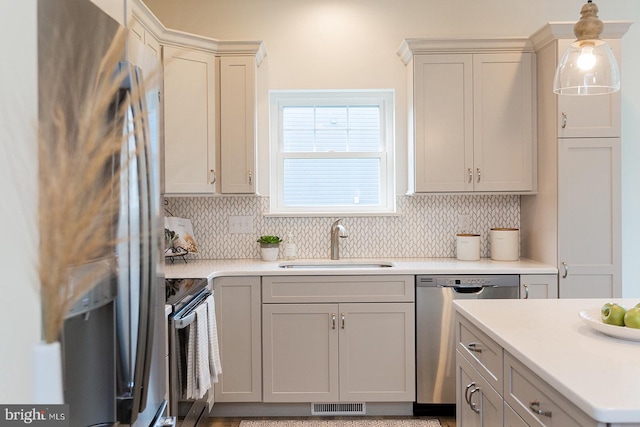 kitchen featuring pendant lighting, stainless steel appliances, tasteful backsplash, gray cabinetry, and sink