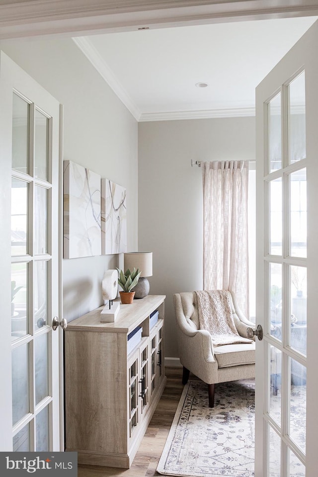 sitting room featuring french doors, ornamental molding, and light hardwood / wood-style flooring