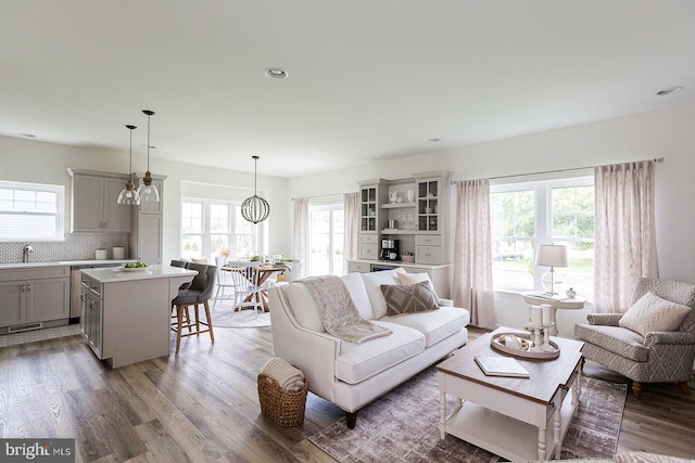 living room with an inviting chandelier, sink, hardwood / wood-style flooring, and a wealth of natural light