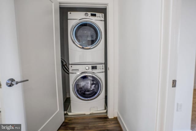 washroom featuring stacked washer and dryer and dark wood-type flooring