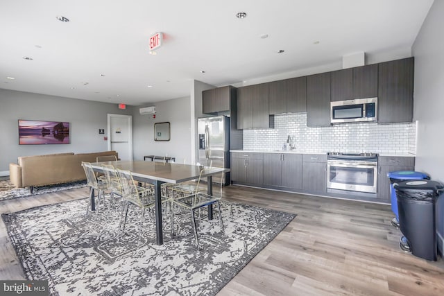 kitchen with backsplash, light hardwood / wood-style floors, sink, stainless steel appliances, and dark brown cabinetry