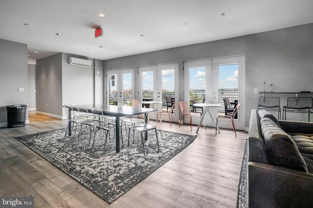 dining room with light hardwood / wood-style flooring, a wall mounted AC, and french doors