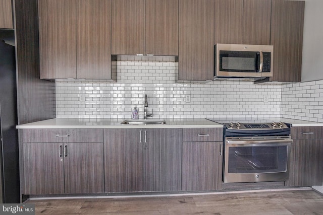 kitchen with backsplash, stainless steel appliances, sink, and hardwood / wood-style flooring