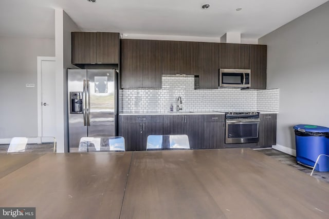 kitchen with dark brown cabinets, dark hardwood / wood-style floors, stainless steel appliances, backsplash, and sink