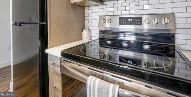 details featuring stainless steel electric stove, tasteful backsplash, and fridge