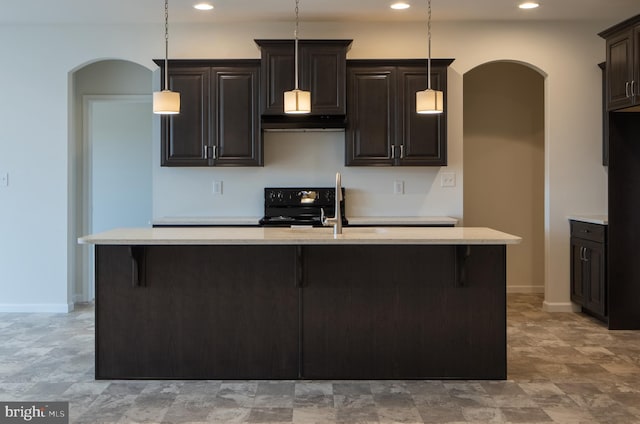 kitchen featuring decorative light fixtures, stove, light tile floors, and an island with sink