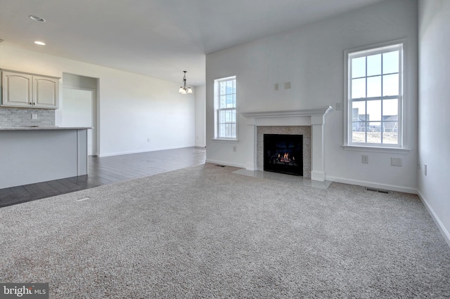 unfurnished living room featuring a notable chandelier and dark carpet