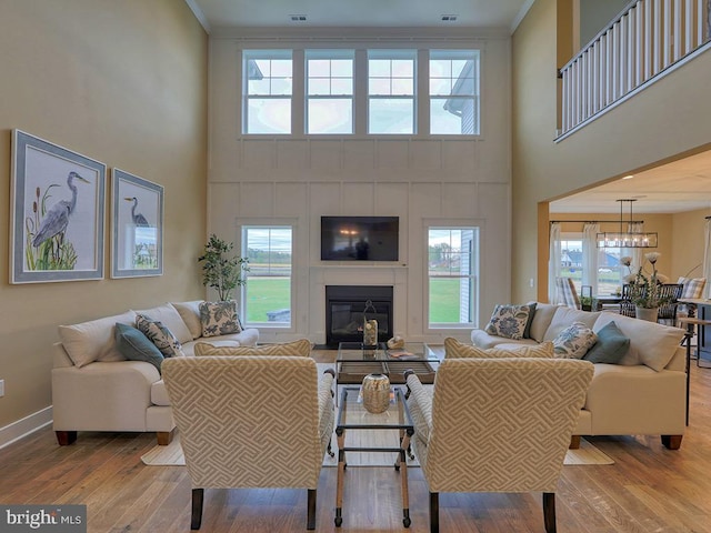 living room with an inviting chandelier, a towering ceiling, and light wood-type flooring