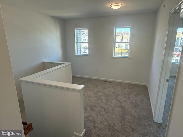 unfurnished room featuring carpet flooring, visible vents, and baseboards