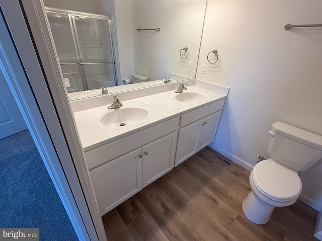 full bathroom with toilet, a shower stall, a sink, and wood finished floors