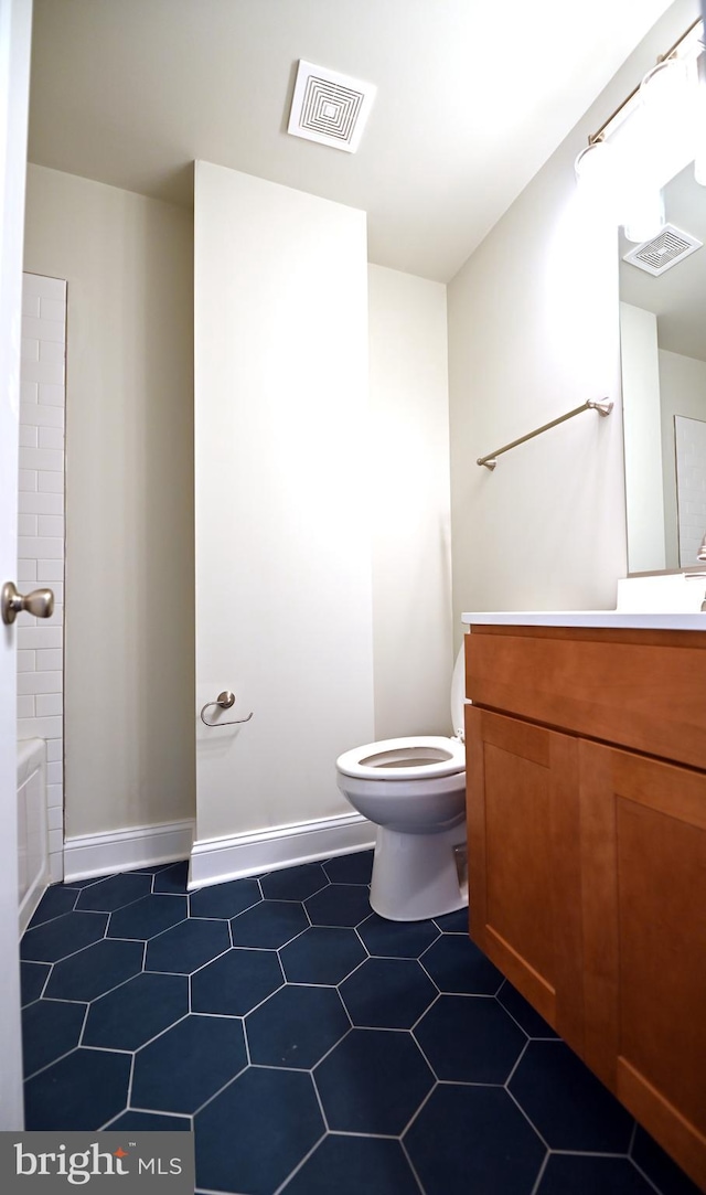 bathroom with toilet, tile floors, and vanity