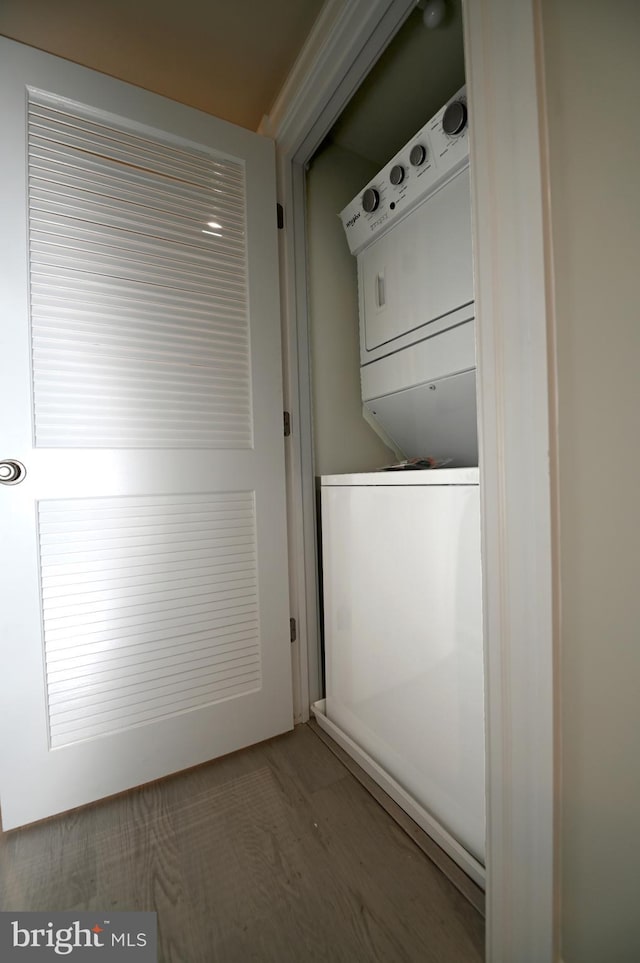 clothes washing area featuring stacked washer and dryer and dark hardwood / wood-style floors