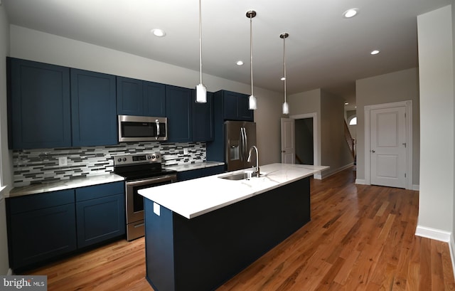 kitchen featuring stainless steel appliances, decorative light fixtures, light hardwood / wood-style flooring, backsplash, and sink