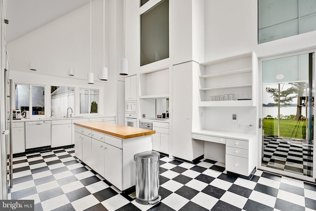 kitchen featuring white appliances, sink, white cabinets, a high ceiling, and a center island