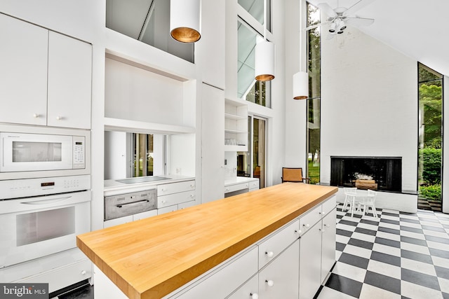 kitchen featuring a healthy amount of sunlight, white appliances, a high ceiling, and white cabinetry