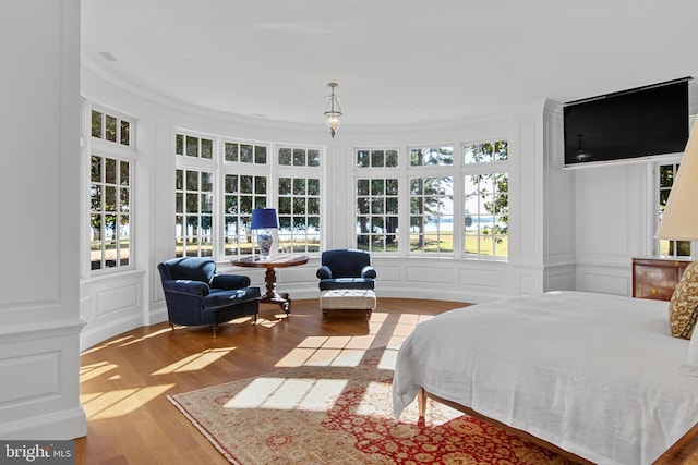 bedroom featuring wood-type flooring, multiple windows, and ornamental molding