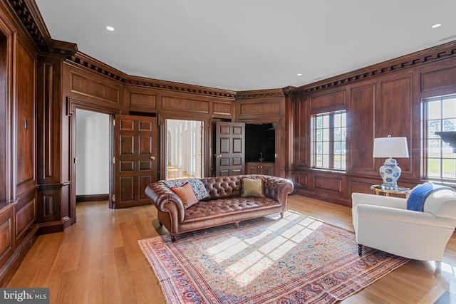 living room with wood walls, light hardwood / wood-style floors, and ornamental molding