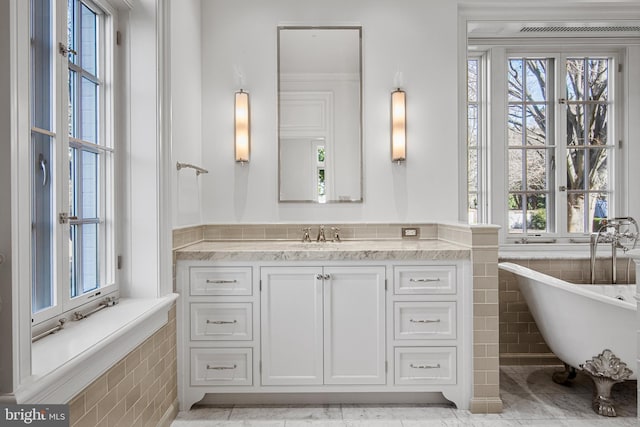 bathroom featuring tile patterned floors, tiled bath, vanity, and a healthy amount of sunlight