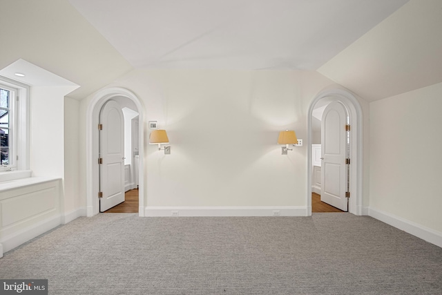 spare room with light colored carpet and lofted ceiling