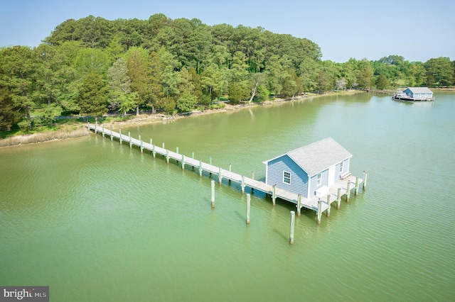 view of dock with a wooded view and a water view