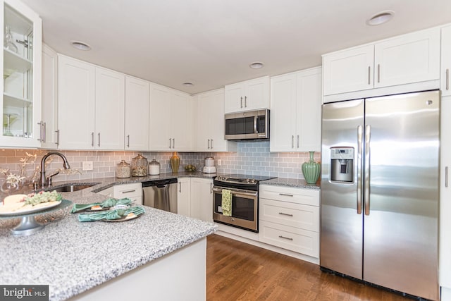 kitchen with appliances with stainless steel finishes, backsplash, dark wood-type flooring, sink, and white cabinets