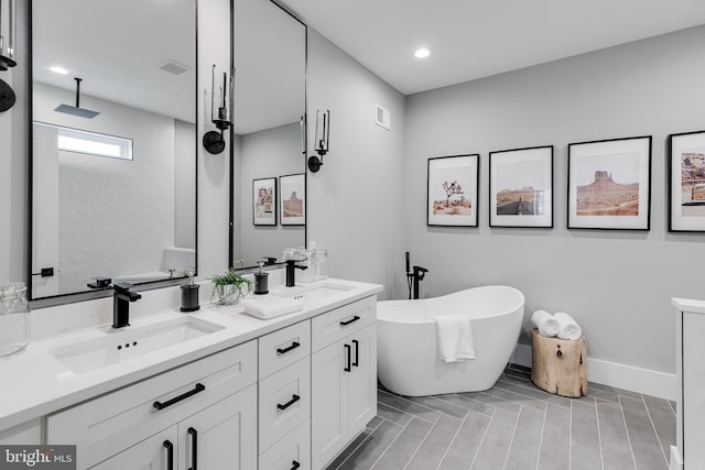 bathroom featuring double sink, a washtub, and vanity with extensive cabinet space