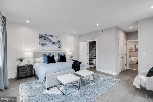 bedroom with ensuite bathroom, a closet, and hardwood / wood-style flooring