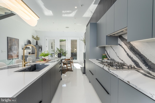 kitchen with light tile floors, gray cabinets, stainless steel gas cooktop, ventilation hood, and sink