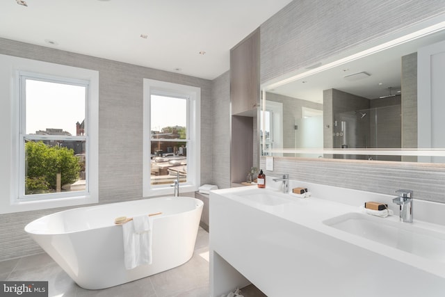 bathroom with dual sinks, tile flooring, and plenty of natural light