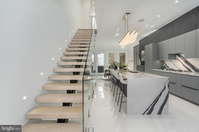 stairs with light tile floors, french doors, and sink