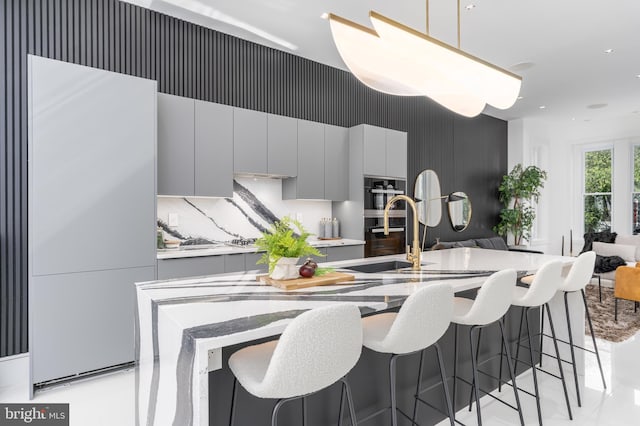 kitchen with a kitchen breakfast bar, double oven, decorative light fixtures, and gray cabinets