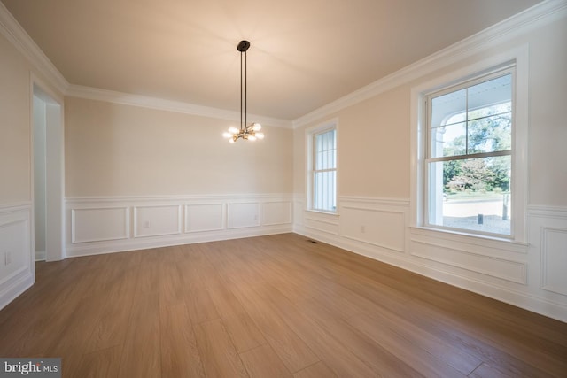 spare room with ornamental molding, a notable chandelier, and light hardwood / wood-style flooring