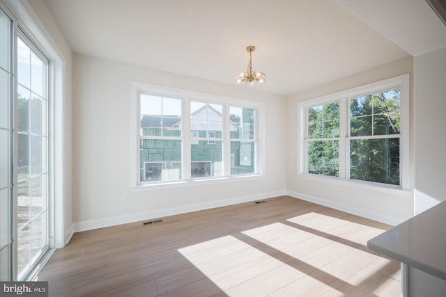 spare room with an inviting chandelier and light hardwood / wood-style floors