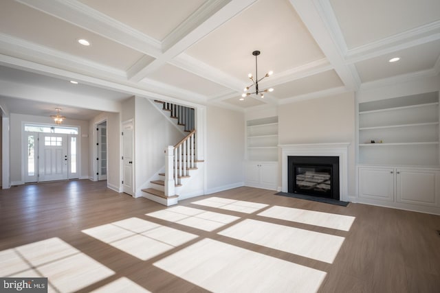 unfurnished living room with a notable chandelier, beamed ceiling, coffered ceiling, and light hardwood / wood-style flooring