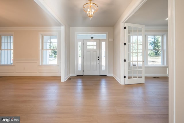 entrance foyer featuring light hardwood / wood-style flooring, ornamental molding, and a chandelier