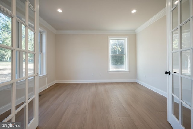 empty room with ornamental molding, light hardwood / wood-style flooring, and french doors