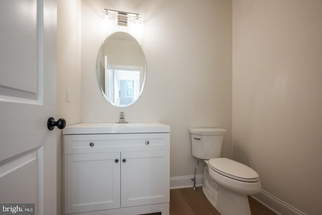 bathroom featuring toilet, vanity, and hardwood / wood-style floors