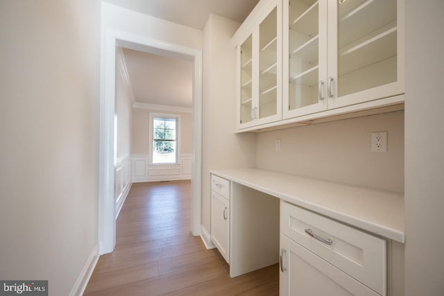 interior space with ornamental molding, white cabinetry, and light hardwood / wood-style flooring