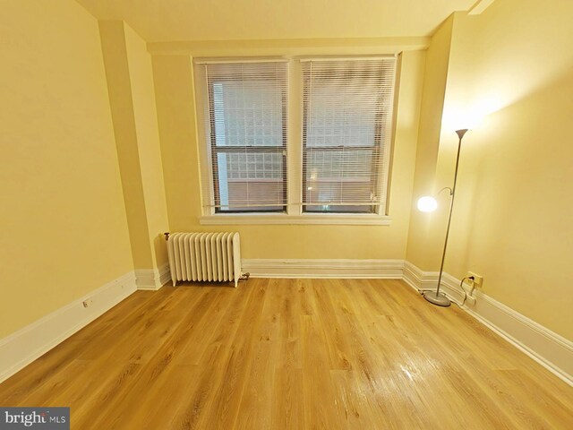 empty room with hardwood / wood-style floors and radiator heating unit