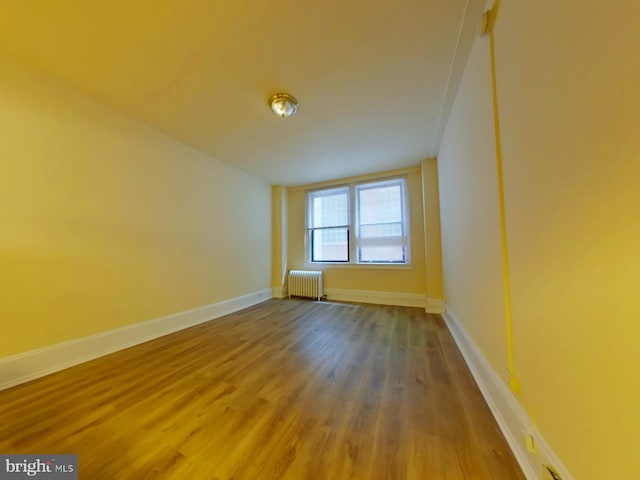 unfurnished room with radiator and wood-type flooring